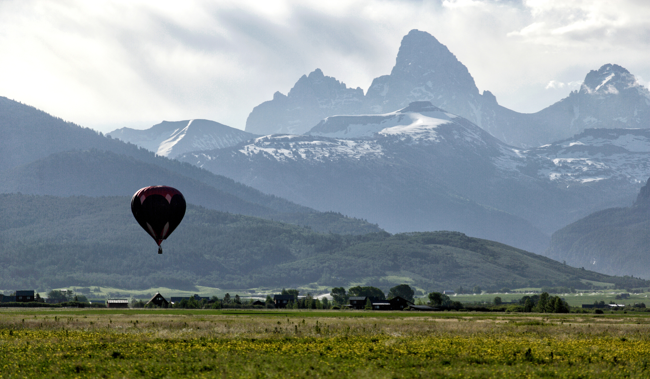 Hot air balloon over ranch country beneath the Tetons